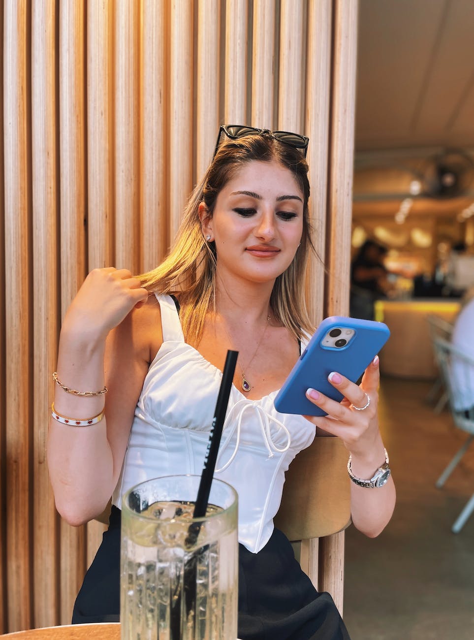 woman in white top using phone in restaurant